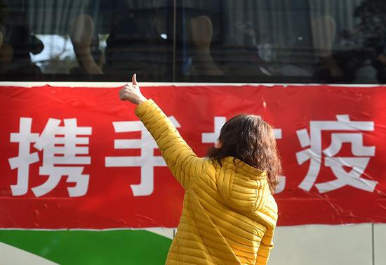 2月9日，在位于杭州的浙江省人民医院，一名前来送行的妇女向医疗队队员竖起大拇指“点赞”。来源：新华社